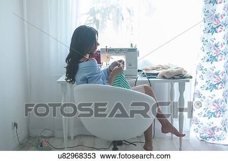 Woman using sewing machine beside window View Large Photo Image Stock Image - Woman using sewing machine beside window. Fotosearch