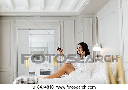 Woman using smartphone and remote control in suite View Large Photo Image Stock Image - Woman using smartphone and remote control in suite. Fotosearch