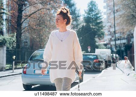 Stock Photo - Woman walking on sunny street, Milan, Italy. Fotosearch