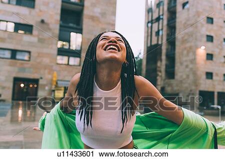 Stock Image - Woman welcoming rain in town square, Milan, Italy. Fotosearch