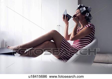 Stock Photograph - Woman with hair-rollers putting on make up. Fotosearch