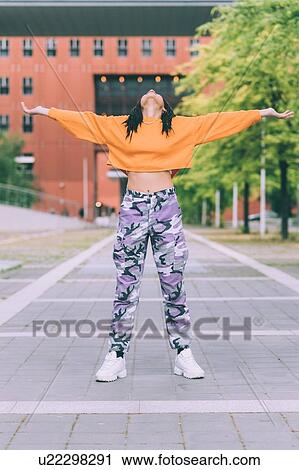Stock Image - Woman with head back and open arms, Milan, Italy. Fotosearch