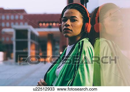 Woman with headphones leaning against glass window, Milan, Italy View Large Photo Image Stock Image - Woman with headphones leaning against glass window, Milan, Italy. Fotosearch