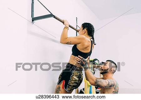 Stock Image - Woman working out on metal bars. Fotosearch