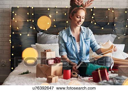 Woman wrapping Christmas presents on bed View Large Photo Image Stock Photo - Woman wrapping Christmas presents on bed. Fotosearch