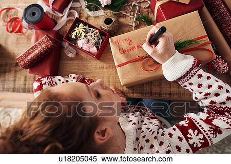 Stock Photography - Woman writing greetings on Christmas presents. Fotosearch
