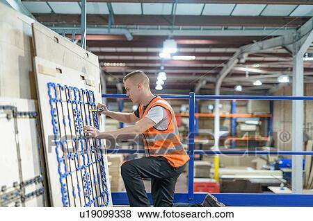 Stock Photo - Worker checking cardboard cutter in cardboard box factory. Fotosearch