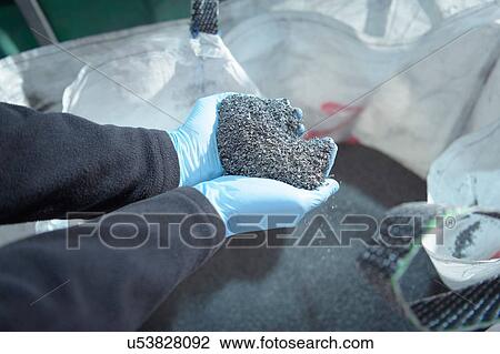 Stock Image - Worker holding recycled metals from catalytic converters in recycling factory. Fotosearch