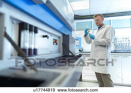 Stock Photo - Worker inspecting acids in laboratory in recycling factory. Fotosearch