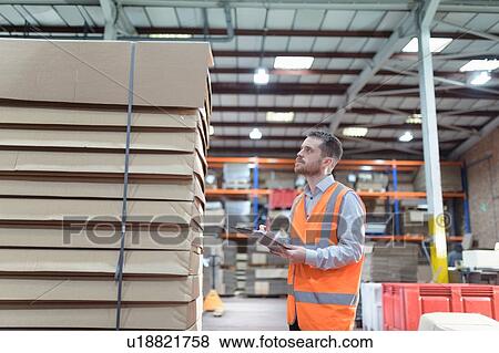 Worker inspecting boxes in cardboard box factory View Large Photo Image Stock Photo - Worker inspecting boxes in cardboard box factory. Fotosearch