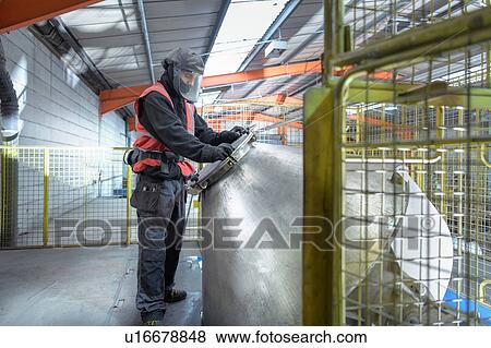 Stock Photo - Worker mixing recycled metals from catalytic converters in recycling factory. Fotosearch