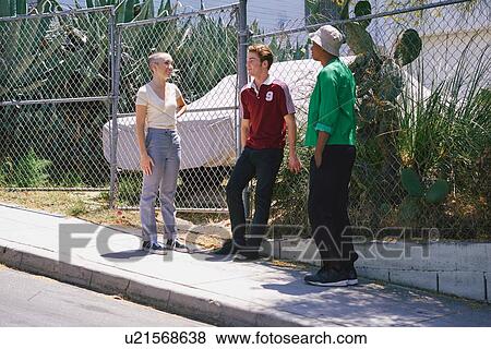 Stock Photo - Young adult friends chatting on suburban sidewalk, Los Angeles, California, USA. Fotosearch