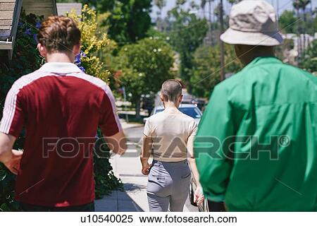 Stock Photography - Young adult friends strolling on suburban sidewalk, rear view, Los Angeles, California, USA. Fotosearch