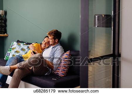 Young couple hugging on couch View Large Photo Image Stock Photo - Young couple hugging on couch. Fotosearch