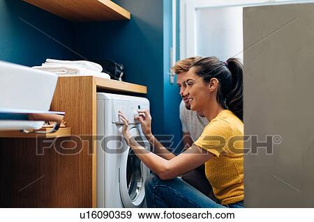 Young couple operating washing machine at home View Large Photo Image Stock Photo - Young couple operating washing machine at home. Fotosearch