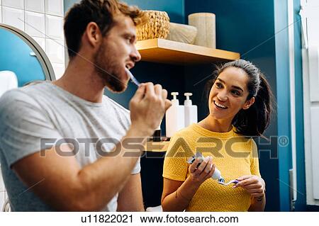 Young couple talking and brushing teeth in bathroom View Large Photo Image Stock Image - Young couple talking and brushing teeth in bathroom. Fotosearch