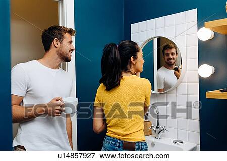 Young couple talking in front of wall mirror in bathroom View Large Photo Image Stock Photo - Young couple talking in front of wall mirror in bathroom. Fotosearch