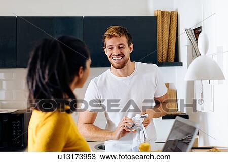 Stock Image - Young couple talking in kitchen. Fotosearch