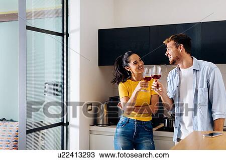 Stock Image - Young couple toasting in kitchen. Fotosearch