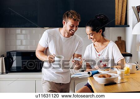 Young couple using smartphone in kitchen View Large Photo Image Stock Image - Young couple using smartphone in kitchen. Fotosearch
