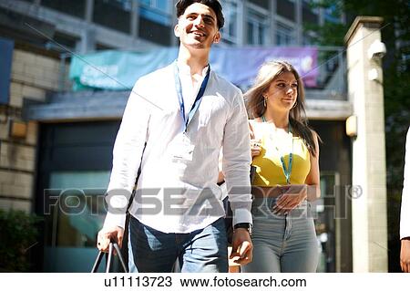 Stock Image - Young male and female higher education students leaving college campus. Fotosearch