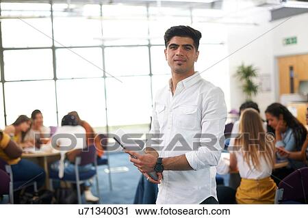 Stock Image - Young male higher education student in college classroom, portrait. Fotosearch