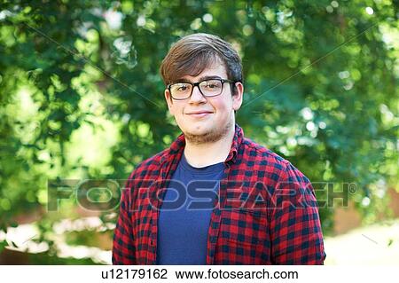 Stock Image - Young male higher education student on college campus, portrait. Fotosearch