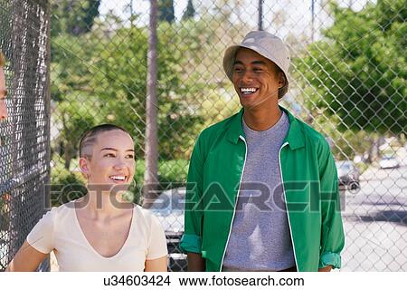 Picture - Young man and female friend by park fence, Los Angeles, California, USA. Fotosearch