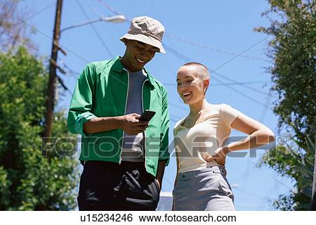 Young man and female friend looking at smartphone in suburbs, Los Angeles, California, USA View Large Photo Image Stock Photograph - Young man and female friend looking at smartphone in suburbs, Los Angeles, California, USA. Fotosearch