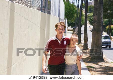 Stock Photo - Young man and girlfriend strolling on suburban sidewalk, Los Angeles, California, USA. Fotosearch