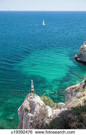 Stock Photograph - Young man doing handstand on coastal rock, Cagliari, Sardinia, Italy. Fotosearch