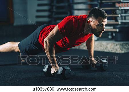 Stock Image - Young man exercising with dumbbells. Fotosearch