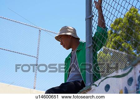 Young man looking out from park fence, low angle view, Los Angeles, California, USA View Large Photo Image Stock Image - Young man looking out from park fence, low angle view, Los Angeles, California, USA. Fotosearch