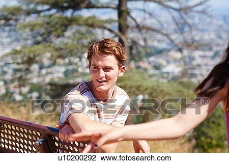 Stock Image - Young man on park bench, Los Angeles, California, USA. Fotosearch
