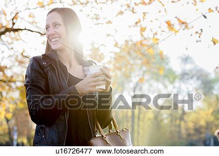 Young woman on coffee break in park View Large Photo Image Stock Photo - Young woman on coffee break in park. Fotosearch