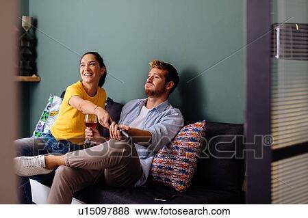 Young woman taking tv remote control from man on couch View Large Photo Image Stock Photo - Young woman taking tv remote control from man on couch. Fotosearch