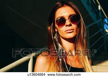Young woman with long brown hair and sunglasses on stairway, head and shoulder portrait View Large Photo Image Picture - Young woman with long brown hair and sunglasses on stairway, head and shoulder portrait. Fotosearch