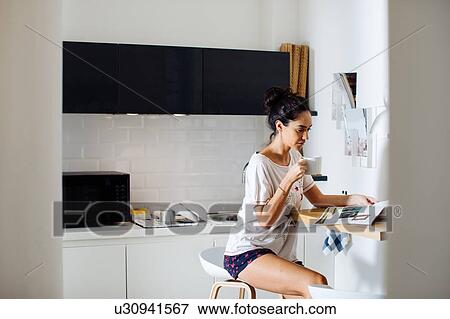 Young woman with mug, reading magazine in kitchen View Large Photo Image Stock Photo - Young woman with mug, reading magazine in kitchen. Fotosearch
