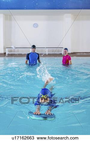 Boy having a swimming lesson with instructor View Large Photo Image Stock Image - Boy having a swimming lesson with instructor. Fotosearch