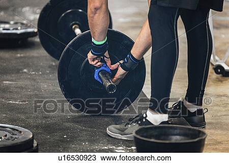 Stock Image - Changing weights on barbell. Fotosearch