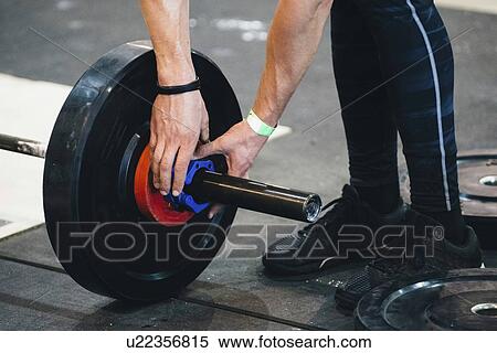 Stock Photography - Changing weights on barbell. Fotosearch