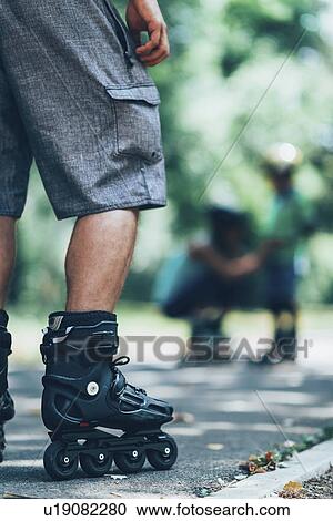 Stock Image - Family roller skating in park. Fotosearch