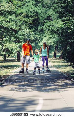 Stock Image - Family roller skating in park. Fotosearch