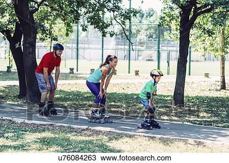 Stock Image - Family roller skating in park. Fotosearch