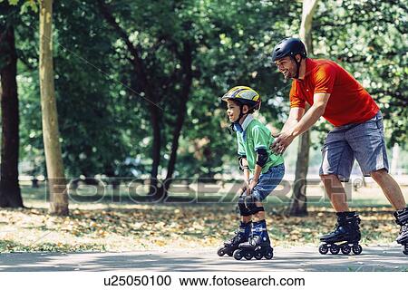 Stock Image - Father and son roller skating in park. Fotosearch