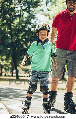 Father roller skating in park with son View Large Photo Image Stock Photo - Father roller skating in park with son. Fotosearch