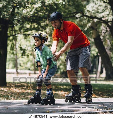 Father teaching son to roller skate in park View Large Photo Image Stock Image - Father teaching son to roller skate in park. Fotosearch