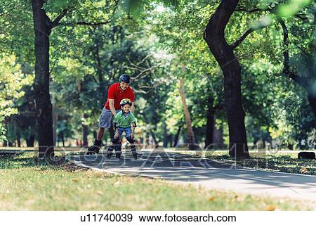Stock Photo - Father teaching son to roller skate in park. Fotosearch