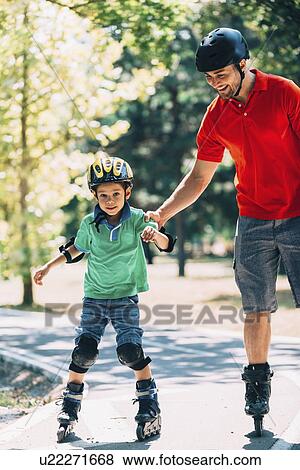 Stock Photo - Father teaching son to roller skate in park. Fotosearch