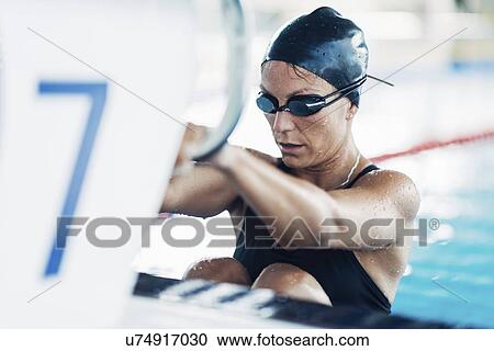 Stock Image - Female swimmer on starting block. Fotosearch